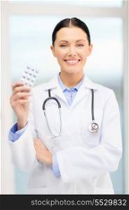 healthcare, pharmacy and medicine concept - smiling young doctor with pills and sthethoscope in cabinet