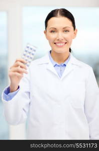 healthcare, pharmacy and medicine concept - smiling young doctor with pills in cabinet