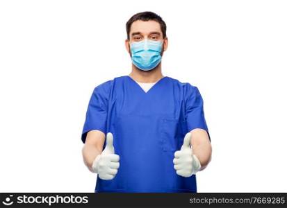 healthcare, profession and medicine concept - doctor or male nurse in blue uniform, face protective medical mask for protection from virus disease and gloves showing thumbs up over white background. male doctor in mask showing thumbs up