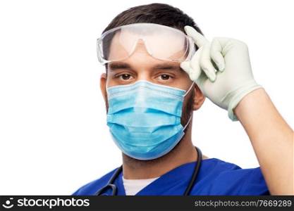 healthcare, profession and medicine concept - doctor or male nurse in blue uniform, face protective medical mask for protection from virus disease, goggles and gloves over white background. male doctor in goggles, mask and gloves