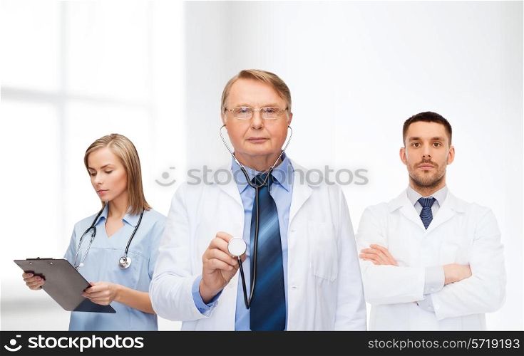 healthcare, profession and medicine concept - group of doctors in white coats with clipboard and stethoscope over clinic background