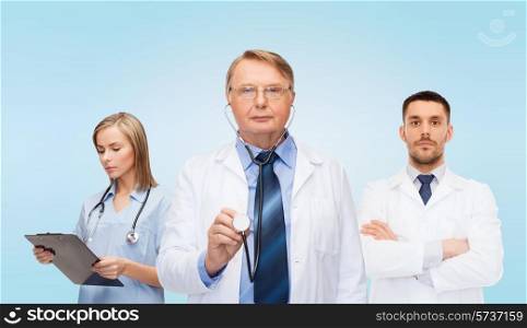 healthcare, profession and medicine concept - group of doctors in white coats with clipboard and stethoscopes over blue background