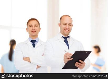healthcare, profession and medicine concept - group of smiling doctors in white coats making notes with clipboard over clinic background