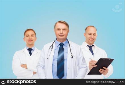 healthcare, profession and medicine concept - group of smiling male doctors in white coats with clipboard and stethoscope over blue background
