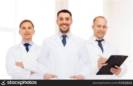 healthcare, profession and medicine concept - group of smiling male doctors in white coats with clipboard and stethoscope over clinic background