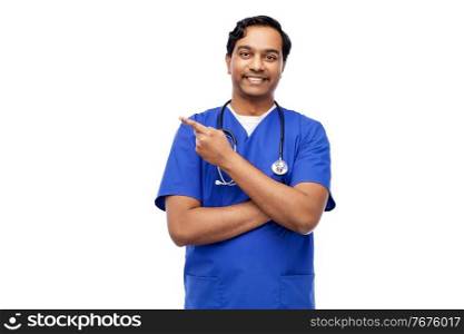 healthcare, profession and medicine concept - happy smiling indian doctor or male nurse in blue uniform holding something imaginary on empty hand over white background. indian male doctor holding something on hand
