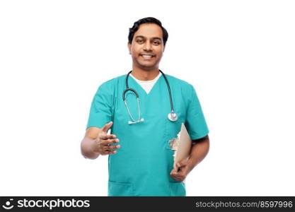 healthcare, profession and medicine concept - happy smiling indian doctor or male nurse in blue uniform with clipboard and stethoscope giving hand for handshake over white background. smiling male doctor giving hand for handshake