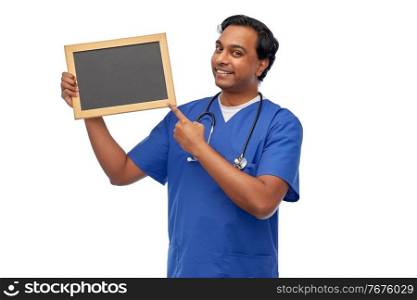 healthcare, profession and medicine concept - happy smiling indian male doctor or nurse in blue uniform with chalkboard and stethoscope over white background. happy indian male doctor or nurse with chalkboard