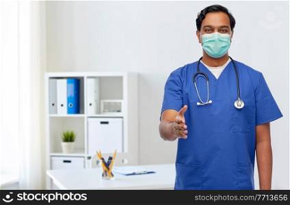 healthcare, profession and medicine concept - indian doctor or male nurse in blue uniform and medical mask giving hand for handshake over medical office at hospital background. indian male doctor in blue uniform and mask