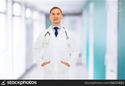 healthcare, profession and medicine concept - smiling male doctor in white coat with stethoscope over hospital background