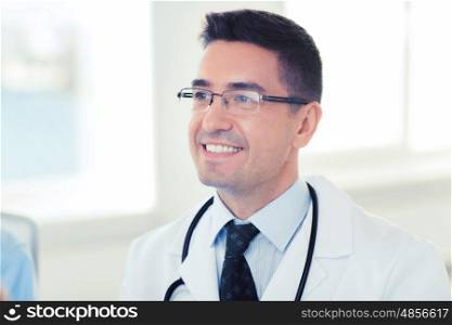 healthcare, profession and medicine concept - smiling male doctor in white coat and eyeglasses at hospital