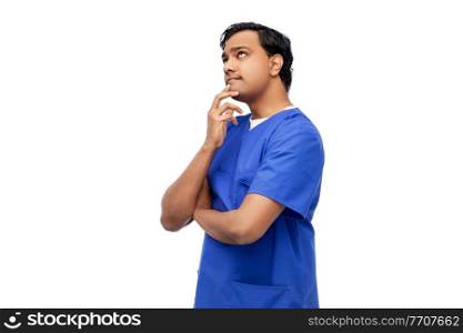 healthcare, profession and medicine concept - thinking indian doctor or male nurse in blue uniform over white background. thinking indian male doctor in blue scrubs