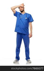 healthcare, profession and medicine concept - tired doctor or male nurse in blue uniform with stethoscope over white background. tired doctor or male nurse with stethoscope