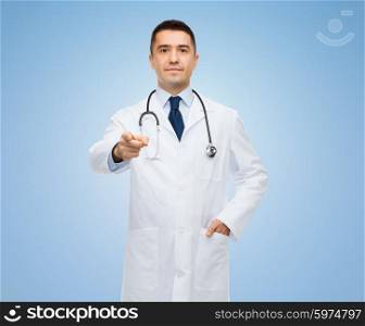 healthcare, profession, gesture, people and medicine concept - male doctor in white coat with stethoscope pointing at you over blue background
