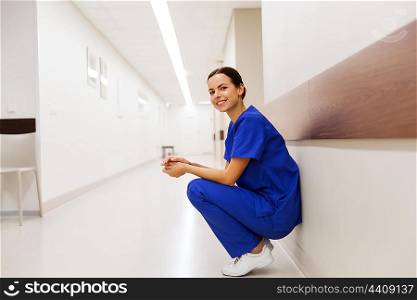 healthcare, profession, people and medicine concept - happy doctor or nurse at hospital corridor