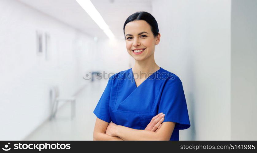 healthcare, profession, people and medicine concept - happy doctor or nurse at hospital corridor. happy doctor or nurse at hospital corridor