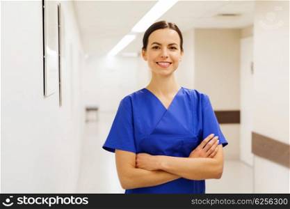 healthcare, profession, people and medicine concept - happy doctor or nurse at hospital corridor