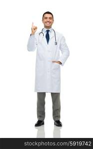 healthcare, profession, people and medicine concept - happy smiling male doctor in white coat pointing finger up