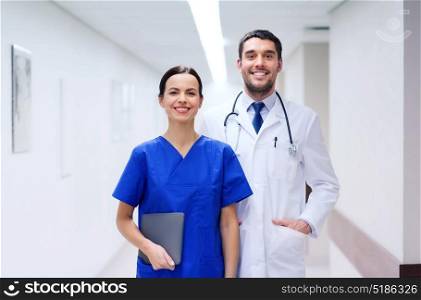 healthcare, profession, people and medicine concept - smiling doctor in white coat and nurse with tablet pc computer at hospital. smiling doctor in white coat and nurse at hospital