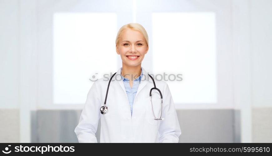 healthcare, profession, people and medicine concept - smiling female doctor in white coat with stethoscope over hospital background