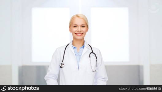 healthcare, profession, people and medicine concept - smiling female doctor in white coat with stethoscope over hospital background