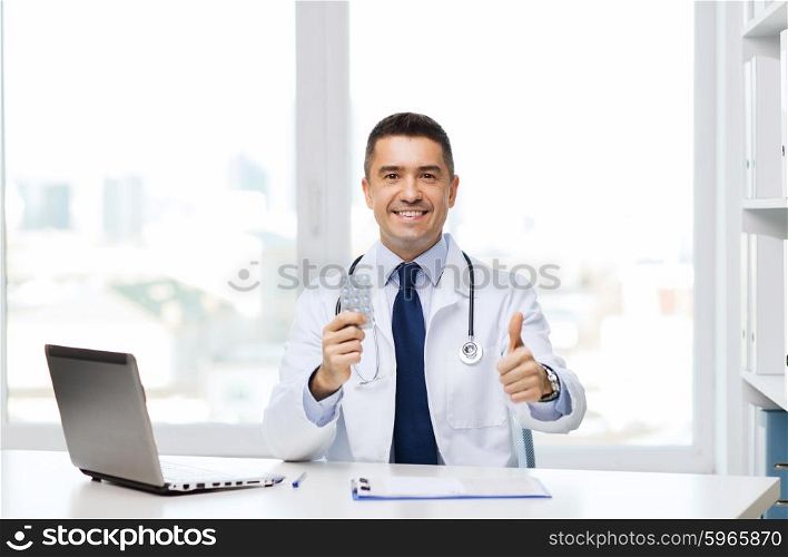 healthcare, profession, people and medicine concept - smiling male doctor in white coat with tablets and laptop computer showing thumbs up in medical office