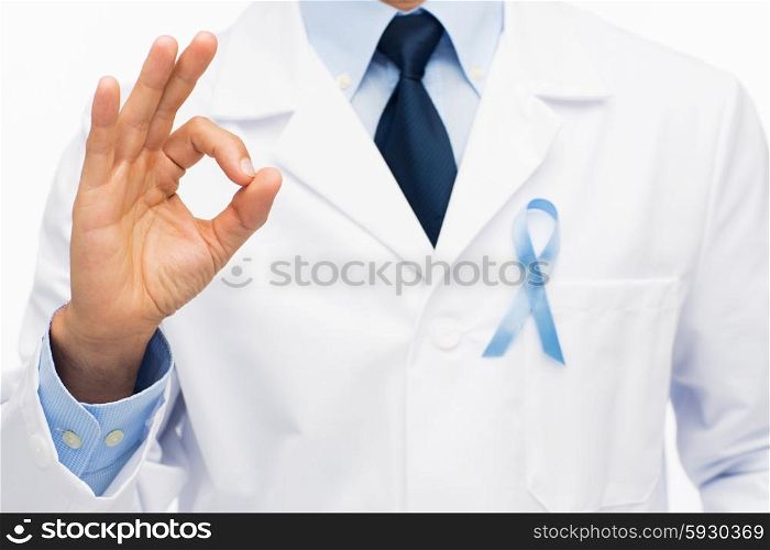 healthcare, profession, people, gesture and medicine concept - close up of male doctor in white coat with sky blue prostate cancer awareness ribbon showing ok hand sign