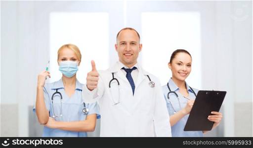 healthcare, profession, people, gesture and medicine concept - group of doctors with syringe and clipboard at hospital showing thumbs up