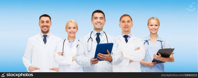 healthcare, profession, people, technology and medicine concept - group of doctors with tablet pc computer and clipboard over blue background