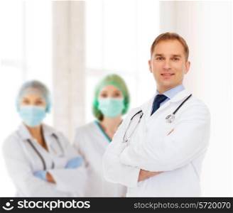 healthcare, profession, teamwork, people and medicine concept - smiling male doctor with stethoscope in white coat over over group of medics