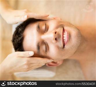 healthcare, spa and beauty concept - man is getting massage at in spa salon