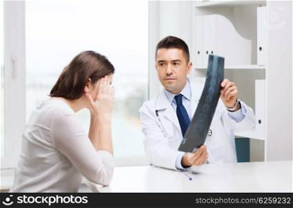 healthcare, surgery, rontgen, people and medicine concept - smiling male doctor in white coat with laptop computer looking at x-ray in medical office