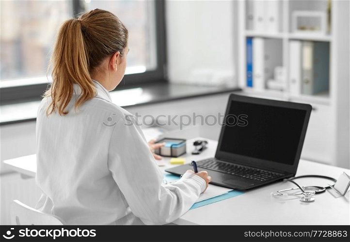 healthcare, technology and medicine concept - female doctor in white coat with laptop computer working at hospital. female doctor with laptop at hospital