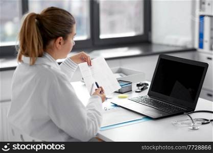 healthcare, technology and medicine concept - female doctor in white coat with laptop computer and cardiogram having video call at hospital. doctor with laptop having video call at hospital