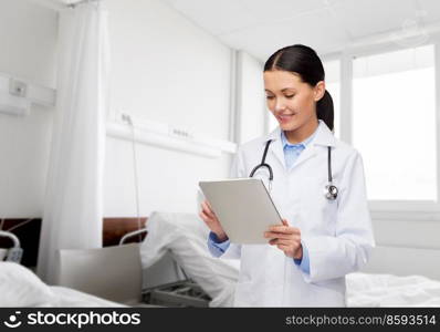 healthcare, technology and medicine concept - smiling female doctor with tablet pc computer over hospital ward background. smiling female doctor with tablet pc in hospital