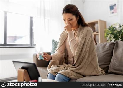 healthcare, technology and people concept - sick asian woman in blanket with medicine having video call on tablet pc computer at home. sick woman with medicine has video consultation