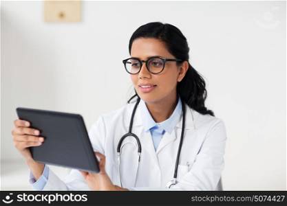 healthcare, technology, people and medicine concept - female doctor in glasses with tablet pc computer in medical office at hospital. female doctor with tablet pc at hospital