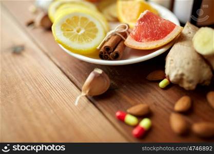 healthcare, traditional medicine and ethnoscience concept - cinnamon, lemon and grapefruit with drug pills on wooden table