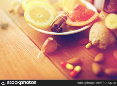 healthcare, traditional medicine and ethnoscience concept - cinnamon, lemon and grapefruit with drug pills on wooden table. traditional medicine and drugs