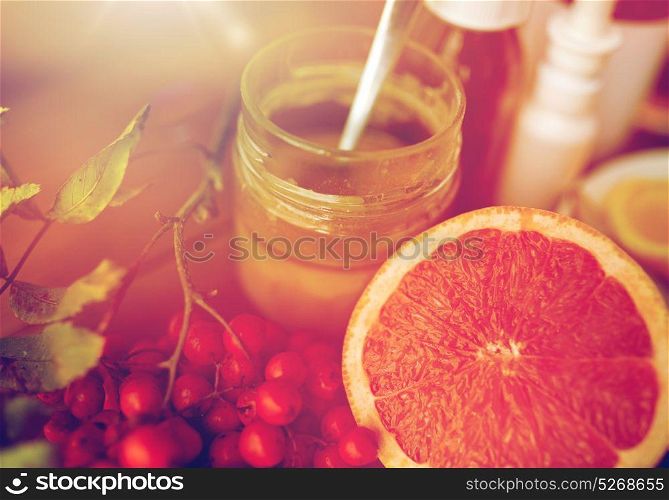 healthcare, traditional medicine and ethnoscience concept - grapefruit, honey with rowanberry and drugs. traditional medicine and drugs