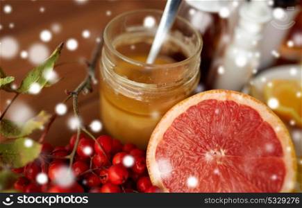 healthcare, traditional medicine and ethnoscience concept - grapefruit, honey with rowanberry and drugs over snow. traditional medicine and drugs