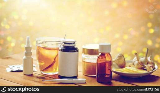 healthcare, traditional medicine and flu concept - drugs, thermometer, honey and cup of tea on wooden table. drugs, thermometer, honey and cup of tea on wood
