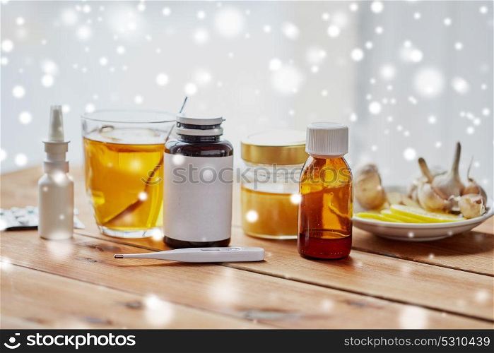 healthcare, traditional medicine, flu and ethnoscience concept - drugs on wooden table over snow. traditional medicine and drugs