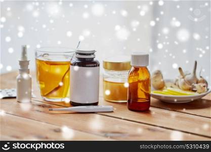 healthcare, traditional medicine, flu and ethnoscience concept - drugs on wooden table over snow. traditional medicine and drugs