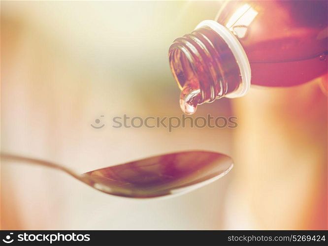 healthcare, treatment and medicine concept - bottle of medication or antipyretic syrup and spoon. medication or antipyretic syrup and spoon