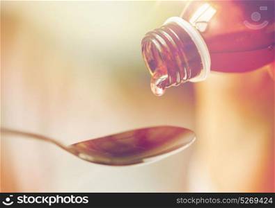healthcare, treatment and medicine concept - bottle of medication or antipyretic syrup and spoon. medication or antipyretic syrup and spoon