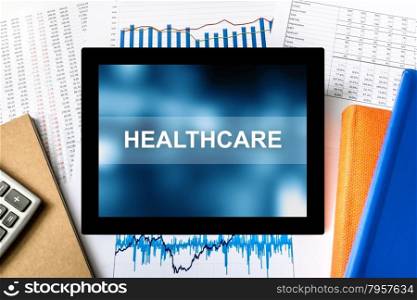 healthcare word on tablet with financial graph background