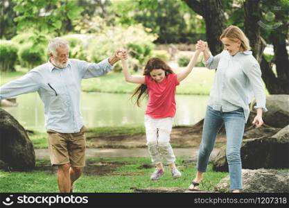 Healthy active father and mother in the park grabbing and playing with daughter child on weekend in summer. Active senior and family lifestyle concept.. Healthy active father and mother play with child.