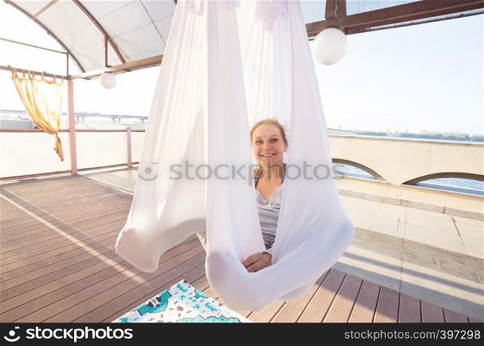 Healthy and fly Yoga Concept. happy smiling girl are sitting in hammocks in a fly yoga class