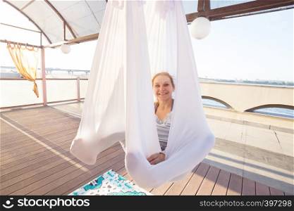 Healthy and fly Yoga Concept. happy smiling girl are sitting in hammocks in a fly yoga class